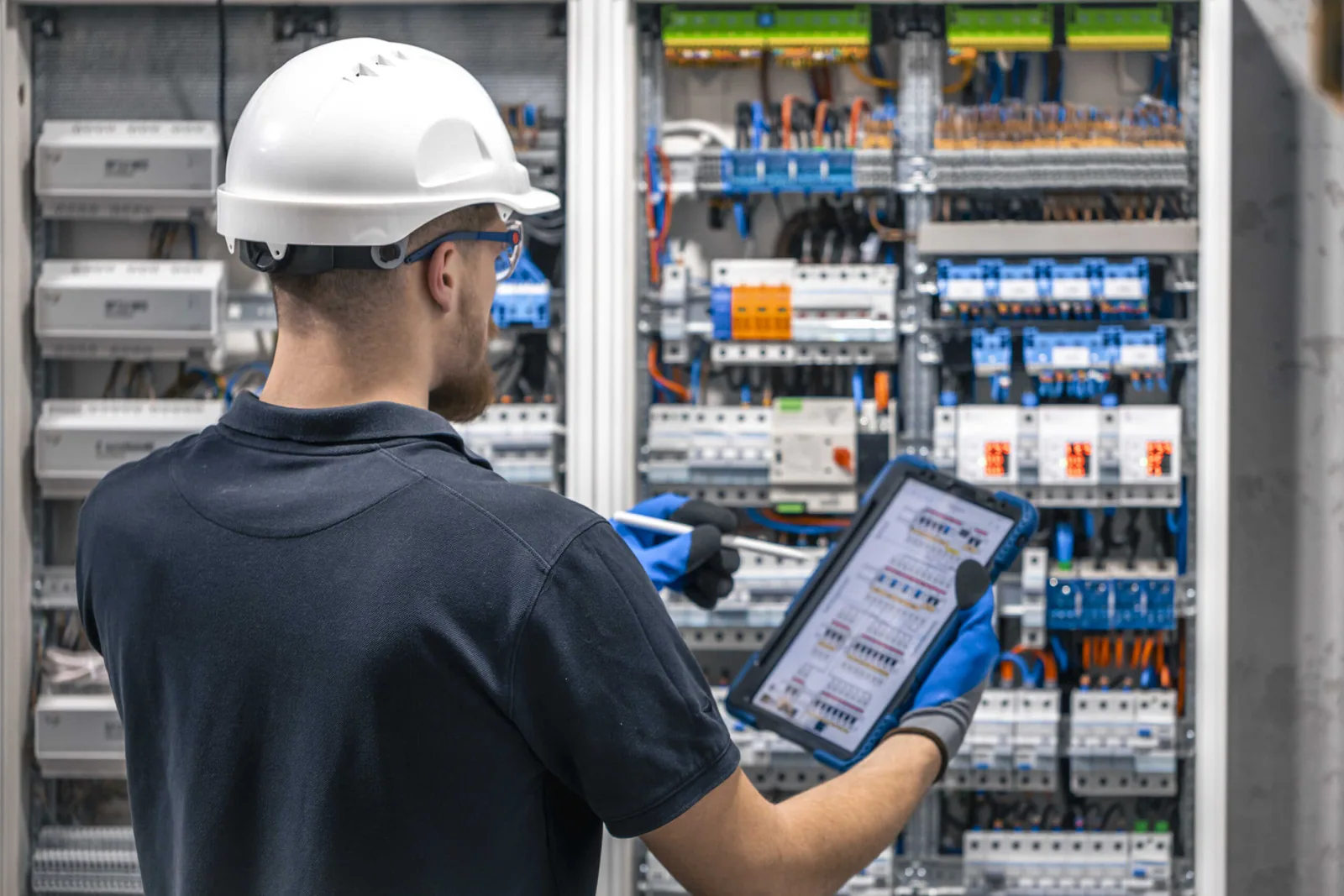 Boletín eléctrico en Tenerife: técnico con casco consultando un esquema en una tableta ante un cuadro eléctrico abierto