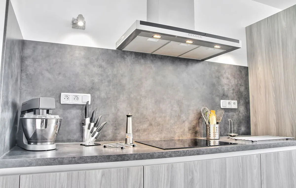 Campana extractora de acero inoxidable con luces encendidas sobre una placa en una cocina gris