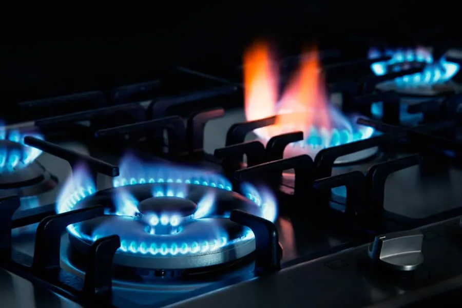 Fuegos de una cocina de gas encendidos, con llamas azules y un quemador con llama anaranjada