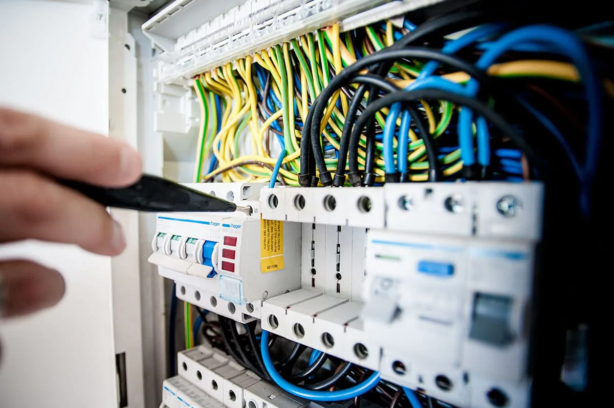 Servicios profesionales: mano con destornillador junto al cableado de un cuadro eléctrico