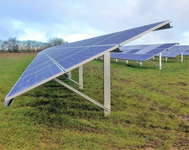 Filas de paneles fotovoltaicos montados sobre estructuras metálicas en un terreno con hierba